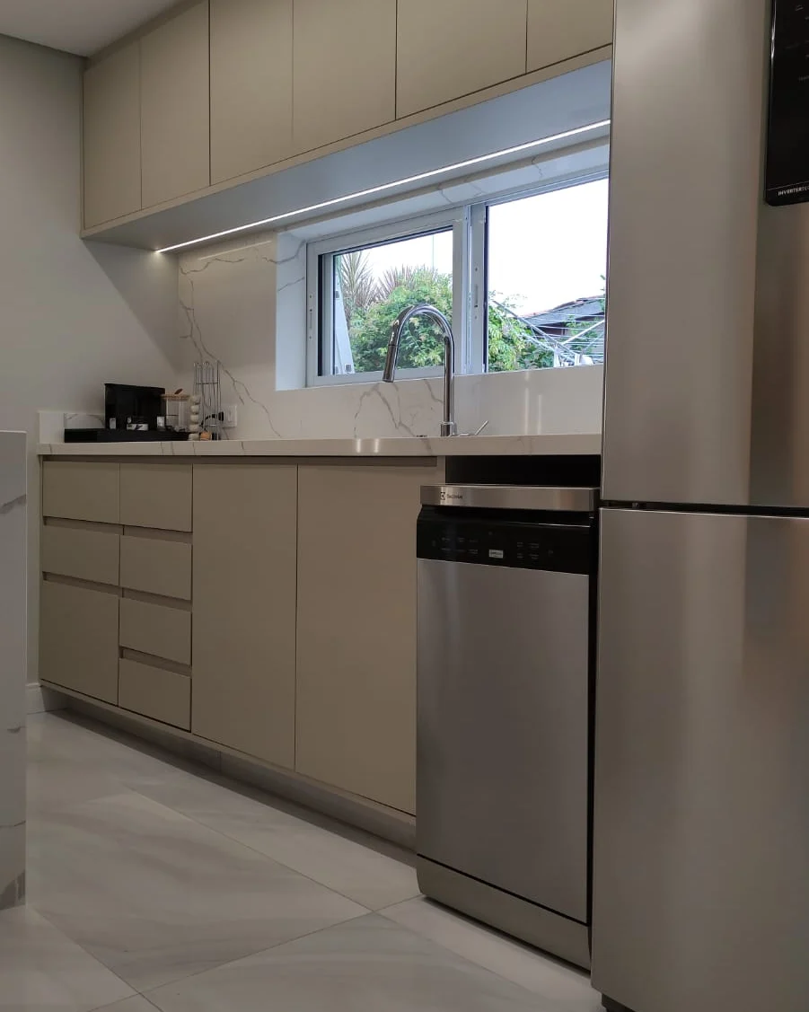 Cozinha com armários altos e LED sob janela